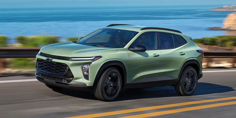 Green Chevrolet Trailblazer driving along a coastal road with the ocean in the background